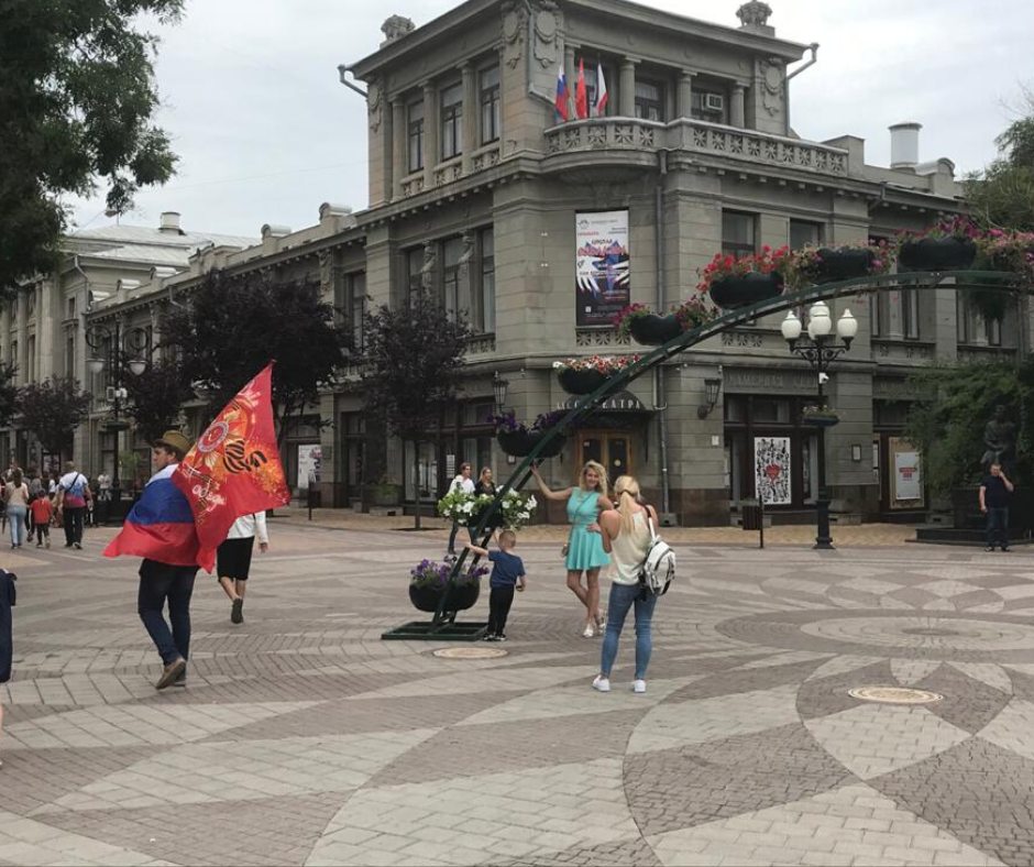 В центре несколько человек активно торгуют советскими и российскими флагами